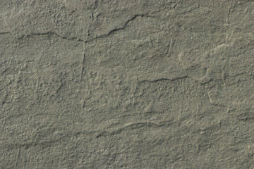 The texture of a dark gray stone with a rough and matte surface. Grunge background with space for text or image. Grey backdrop.