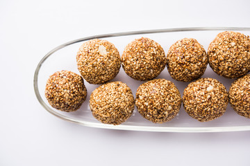 Tilgul Laddu or Til Gul balls for makar sankranti, it's a healthy food made using sesame, crushed peanuts and jaggery. served in a bowl. selective focus showing details.