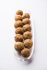 Tilgul Laddu or Til Gul balls for makar sankranti, it's a healthy food made using sesame, crushed peanuts and jaggery. served in a bowl. selective focus showing details.