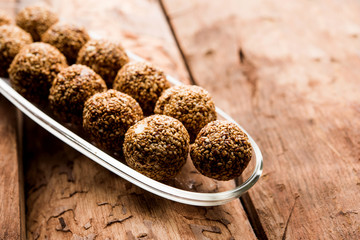 Tilgul Laddu or Til Gul balls for makar sankranti, it's a healthy food made using sesame, crushed peanuts and jaggery. served in a bowl. selective focus showing details.
