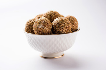 Tilgul Laddu or Til Gul balls for makar sankranti, it's a healthy food made using sesame, crushed peanuts and jaggery. served in a bowl. selective focus showing details.