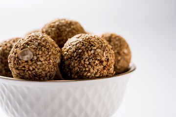 Tilgul Laddu or Til Gul balls for makar sankranti, it's a healthy food made using sesame, crushed peanuts and jaggery. served in a bowl. selective focus showing details.
