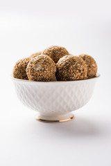 Tilgul Laddu or Til Gul balls for makar sankranti, it's a healthy food made using sesame, crushed peanuts and jaggery. served in a bowl. selective focus showing details.