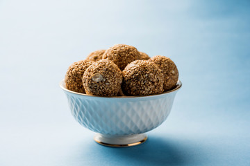 Tilgul Laddu or Til Gul balls for makar sankranti, it's a healthy food made using sesame, crushed peanuts and jaggery. served in a bowl. selective focus showing details.