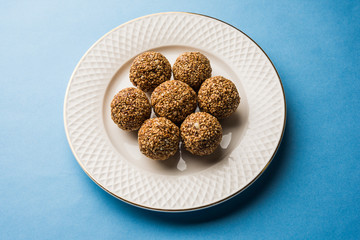Tilgul Laddu or Til Gul balls for makar sankranti, it's a healthy food made using sesame, crushed peanuts and jaggery. served in a bowl. selective focus showing details.