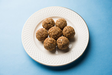 Tilgul Laddu or Til Gul balls for makar sankranti, it's a healthy food made using sesame, crushed peanuts and jaggery. served in a bowl. selective focus showing details.