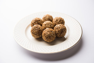 Tilgul Laddu or Til Gul balls for makar sankranti, it's a healthy food made using sesame, crushed peanuts and jaggery. served in a bowl. selective focus showing details.