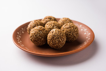 Tilgul Laddu or Til Gul balls for makar sankranti, it's a healthy food made using sesame, crushed peanuts and jaggery. served in a bowl. selective focus showing details.