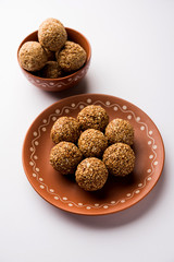 Tilgul Laddu or Til Gul balls for makar sankranti, it's a healthy food made using sesame, crushed peanuts and jaggery. served in a bowl. selective focus showing details.