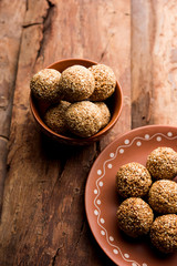Tilgul Laddu or Til Gul balls for makar sankranti, it's a healthy food made using sesame, crushed peanuts and jaggery. served in a bowl. selective focus showing details.