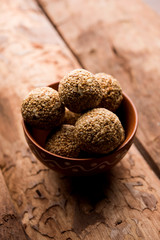 Tilgul Laddu or Til Gul balls for makar sankranti, it's a healthy food made using sesame, crushed peanuts and jaggery. served in a bowl. selective focus showing details.