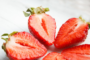 Sliced strawberries on white wooden background. Berry background with place for text. Selective focus.