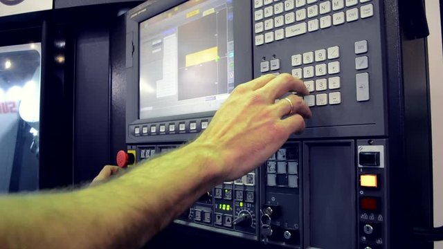 Person works behind the control panel of the production machine at the factory.Industrial machinery, production aggregation and equipment mechanical automaton. Heavy machinery