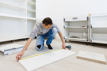 Young man dressed casual assembling furniture in new house