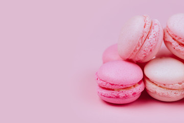 Group of sweet pink and white mini macarons on soft pink paper background with copy space for adding text