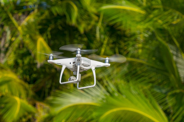 Drone in flight, green trees in the background, selective focus on the drone. - Powered by Adobe