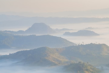 Fototapeta premium Mountain view morning of the hill around with the ocean of mist with blue sky background, sunrise at Tham Sakoen View Point attraction on route 1148, Tham Sakoen National Park, Nan Province, Thailand.