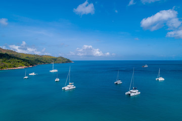Fototapeta na wymiar Spectacular aerial view of some yachts and small boats floating on a clear and turquoise sea, Seychelles in the Indian Ocean.Top view from drone