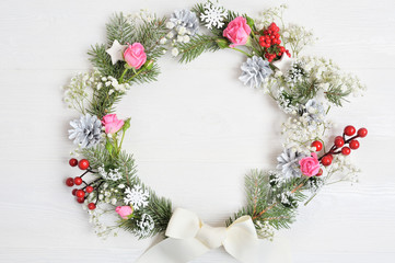 Mockup of Christmas Wreath Made of Naturalistic Looking Pine Branches Decorated with Red Berries. Flat lay on a white wooden background, with place for your text. Top view