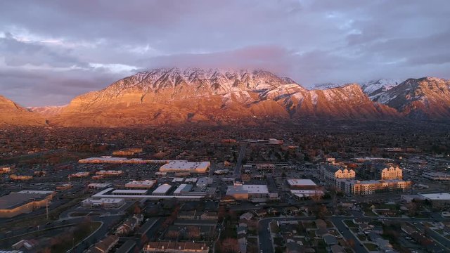 Aerial view of buildings lit up by the sun in Utah Valley on State Street in Orem during winter solstice with holiday traffic.