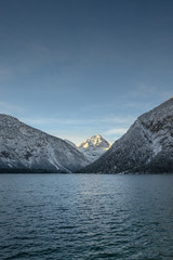 alpine lake plansee while sunrise with lighted mountain thaneller at winter
