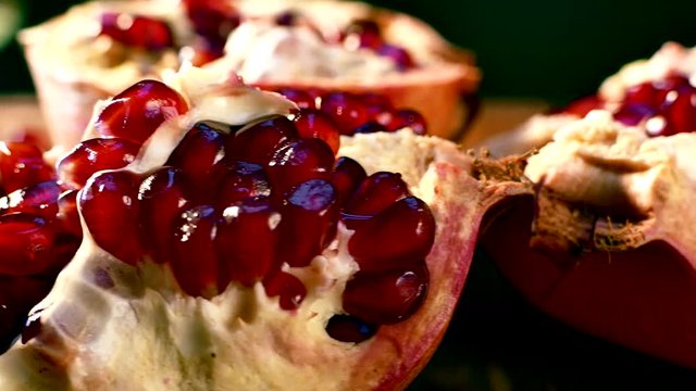 Pomegranate fruit is broken into pieces. Pomegranate seeds lie on a platter. Juicy red fruit on a cutting board. Beautiful pomegranate pulp.
