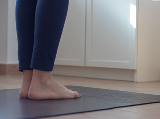 Feet of woman on a yoga mat practicing at home