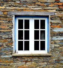 Rustic hand-hewn wood window set into a stone wall built from schist in Piodão, made of shale rocks stack, one of Portugal's schist villages in the Aldeias do Xisto.