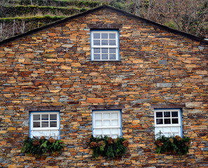 Rustic hand-hewn wood window set into a stone wall built from schist in Piodão, made of shale rocks stack, one of Portugal's schist villages in the Aldeias do Xisto.