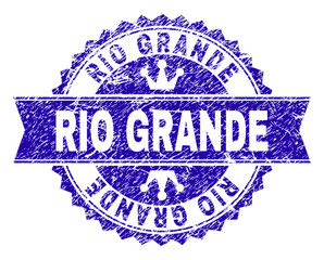 RIO GRANDE rosette seal watermark with distress effect. Designed with round rosette, ribbon and small crowns. Blue vector rubber watermark of RIO GRANDE tag with scratched texture.