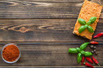 Hummus with sweet paprika and basil leaves on brown table, space for text.