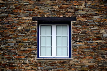 Fototapeta na wymiar Rustic hand-hewn wood window set into a stone wall built from schist in Piodão, made of shale rocks stack, one of Portugal's schist villages in the Aldeias do Xisto.