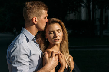 black background. happy, loving couple hugging. boyfriend kissing girl and hugging from behind, protection. protects. smiles