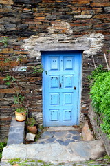 Rustic hand-hewn wood door set into a stone wall built from schist in Piodão, made of shale rocks stack, one of Portugal's schist villages in the Aldeias do Xisto.