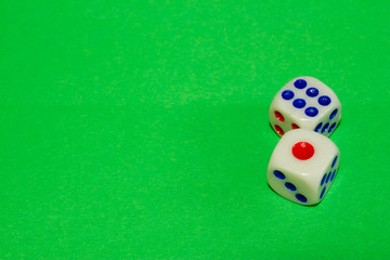 Two white dices with red and blue dots on green table. Casino gambling concept image
