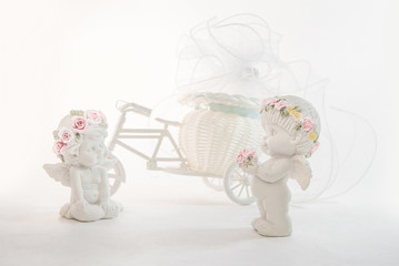 Clay figurines of white angels with a Bicycle in the background.