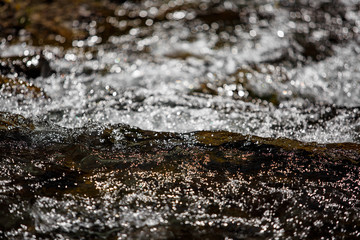 Mountain stream flowing fast in spring. Water texture