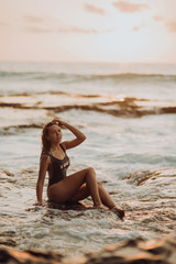 Fototapeta na wymiar sexy women on a tropical beach in waves . sea, ocean sunset rocks on background
