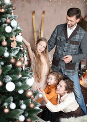 happy family decorates the Christmas tree in their living room.