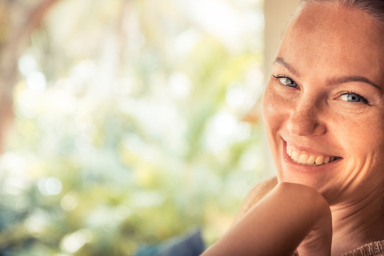 Young beautiful happy smiling tanned woman looking at camera portrait sunny day with copy space during tropical summer holidays 