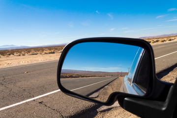 Looking through a rear view mirror  on a pickup truck in the Mojave Desert in California