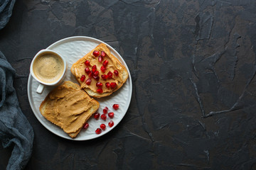 Sandwich with peanut paste and pomegranate grain red - breakfast or sweet snack (dessert). Top view. copy space