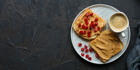 Sandwich with peanut paste and pomegranate grain red - breakfast or sweet snack (dessert). Top view. copy space