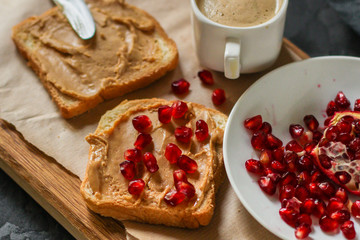 Sandwich with peanut paste and pomegranate grain red - breakfast or sweet snack (dessert). Top view. copy space
