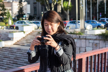 Chinese Girl Standing on the Bridge and Checking Picture She Took With Her Photo Camera