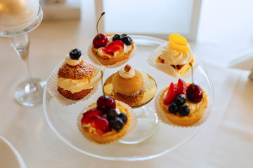 A close-up of mini cakes on a transparent cake stand on a table