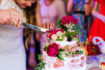 Newlyweds keep knife together and cut delicious wedding cake-cov