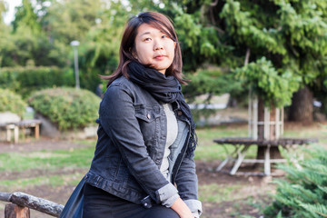 Chinese Girl Standing on the Wooden Bridge and Enjoying Sunny Day in a Park