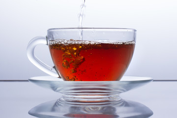 in a transparent cup of tea is poured, black tea is poured, break at work