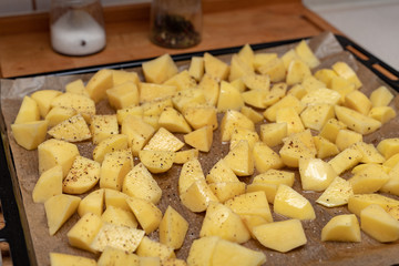 Raw potatoes sprinkled with spices. Vegetables cut into cubes prepared for baking.